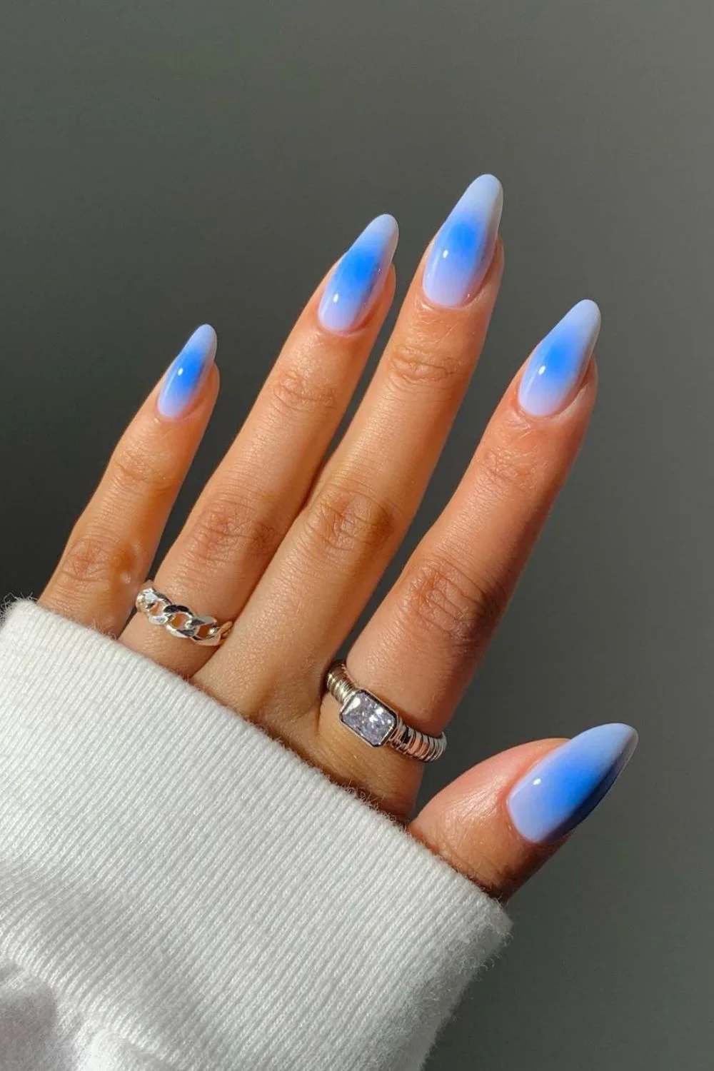 Almond-shaped nails with a blue gradient ombre effect, showcasing a trendy summer 2025 nail design