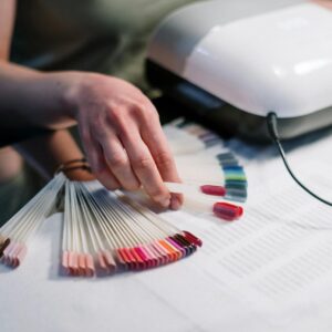 Close-up of a manicurist selecting nail polish colors in a salon setting.