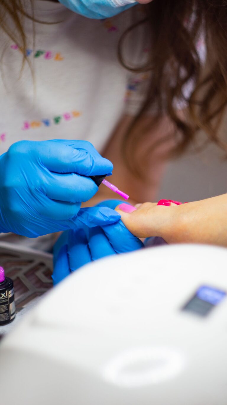 Pedicure hybrydowy - nakładanie lakieru hybrydowego na paznokcie u stóp podczas zabiegu