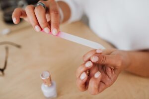 Szklany pilnik do paznokci trzymany w dłoni podczas domowego manicure