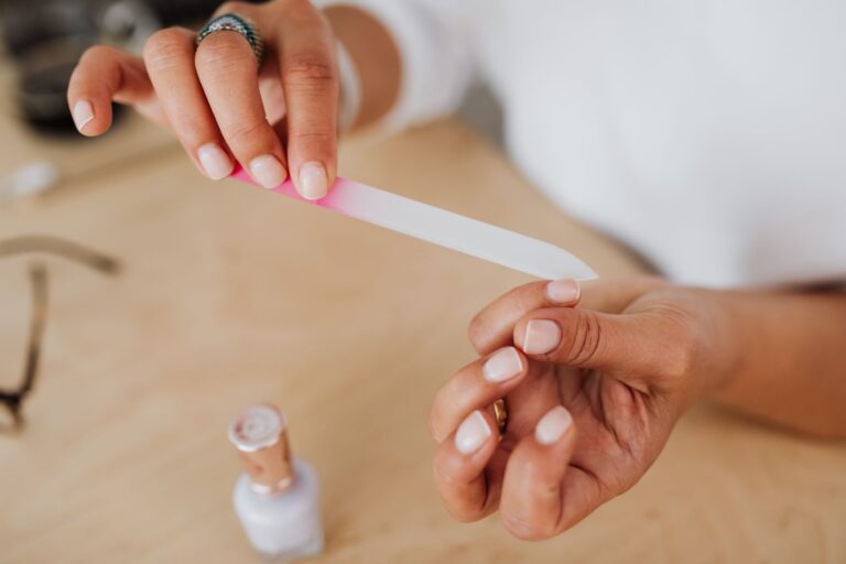 Szklany pilnik do paznokci trzymany w dłoni podczas domowego manicure