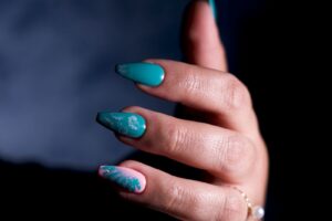 Turkusowy manicure na paznokciach w kształcie trumienki ze srebrnymi metalicznymi akcentami i różowym paznokciem z liściem